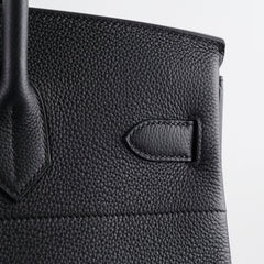 Close-up of a black leather handbag with a visible brand l