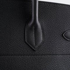 Close-up of a black textured leather bag with a handle.
