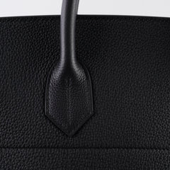 Close-up of a black textured handbag with a handle.