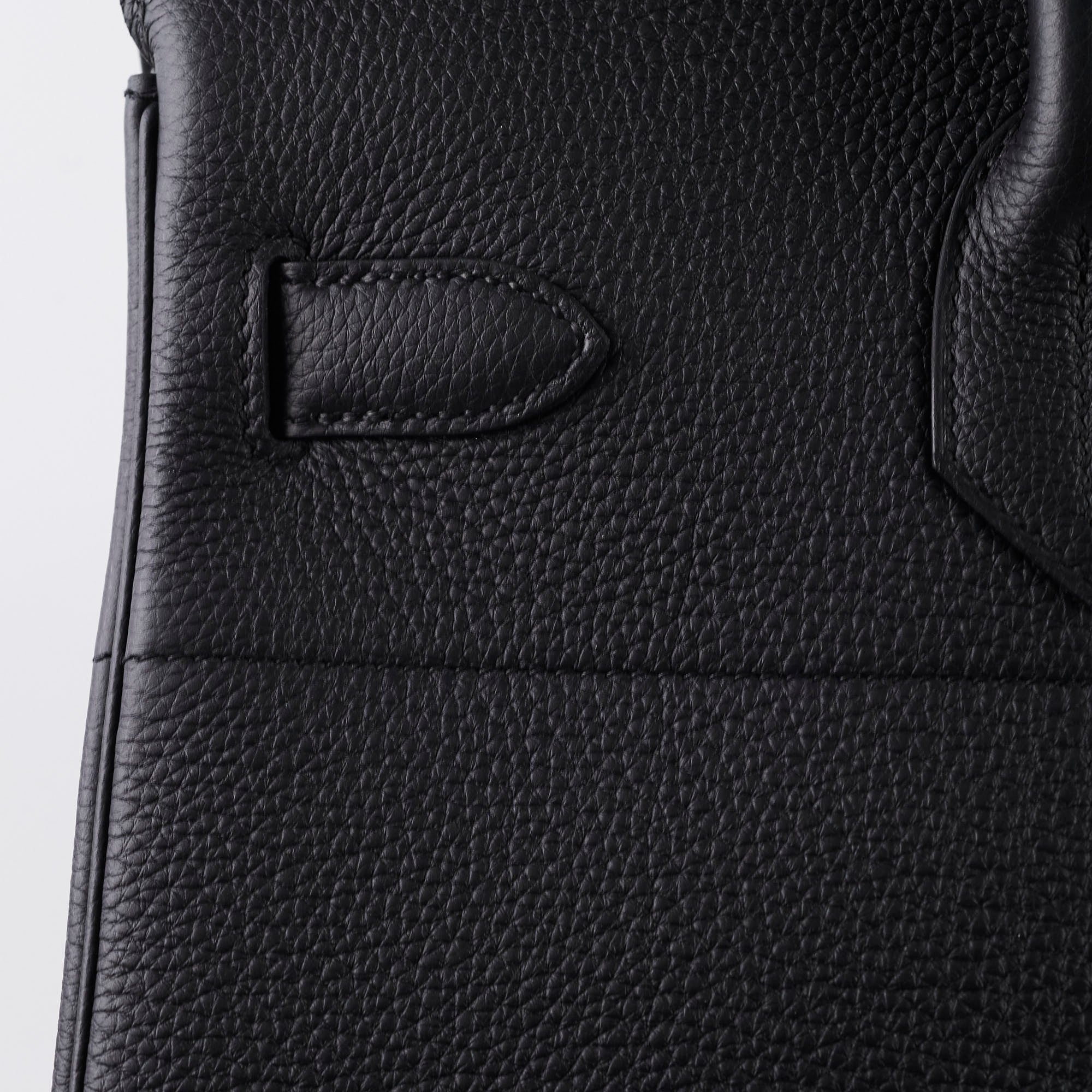 Close-up of a black leather product with a visible brand logo 