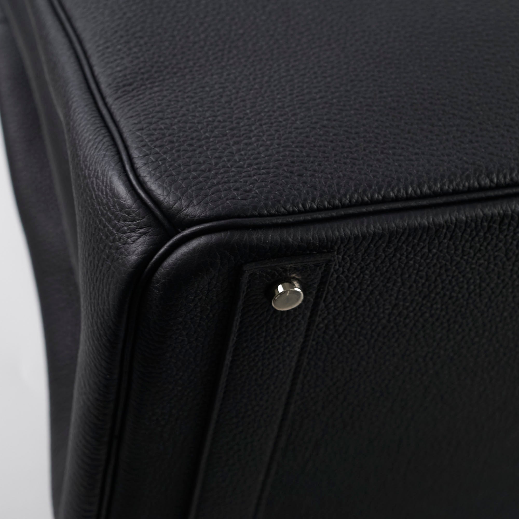 Close-up of a black leather product with a silver button 