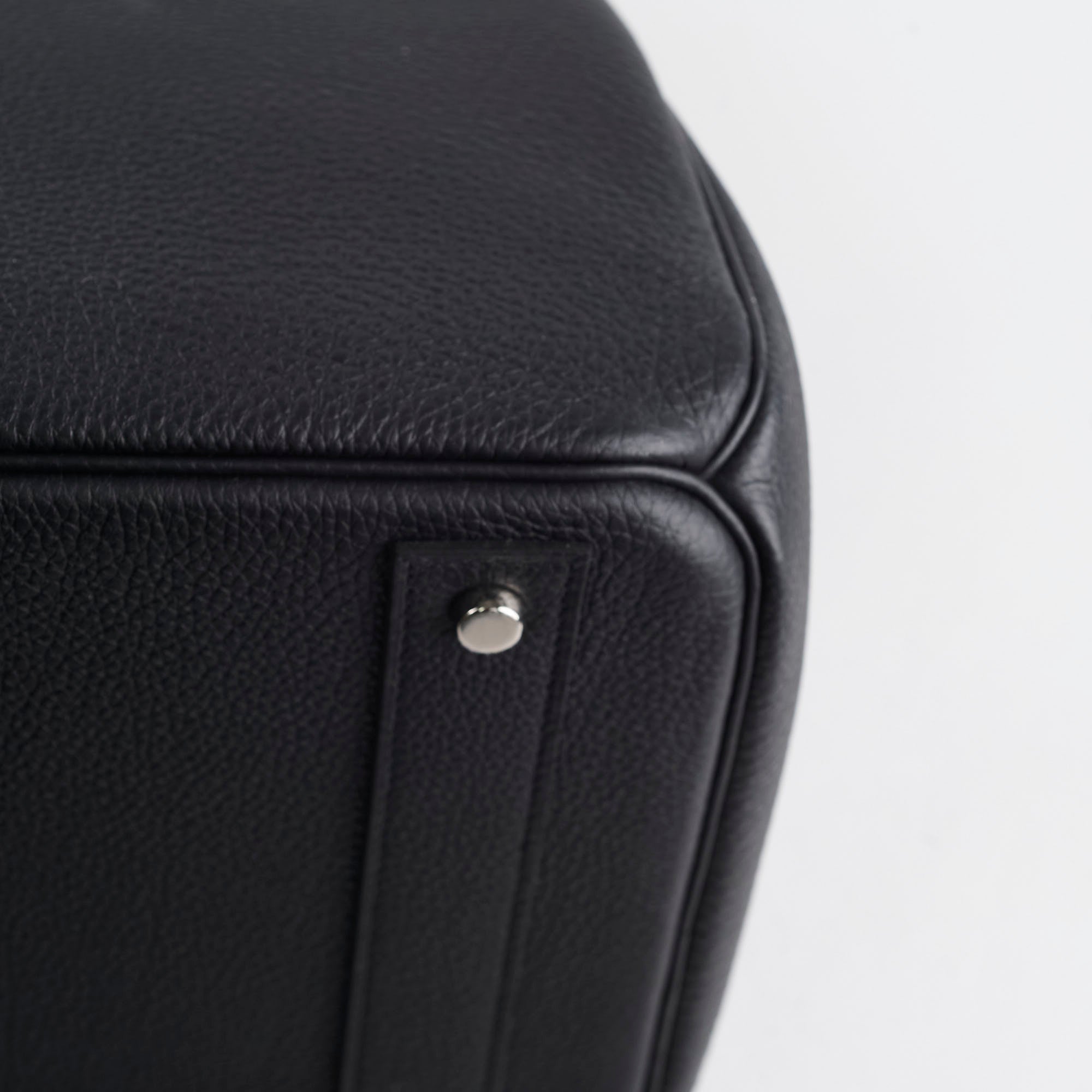 Close-up of a black leather product with a silver button 