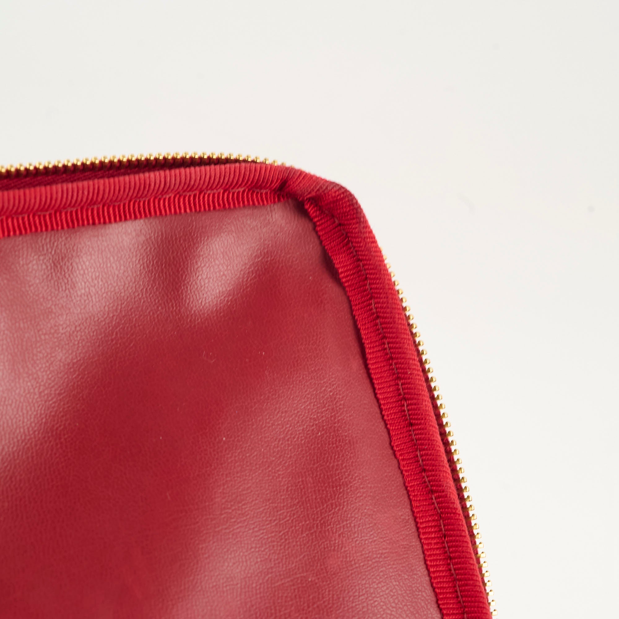 Close-up of a red leather product with a gold zipper 