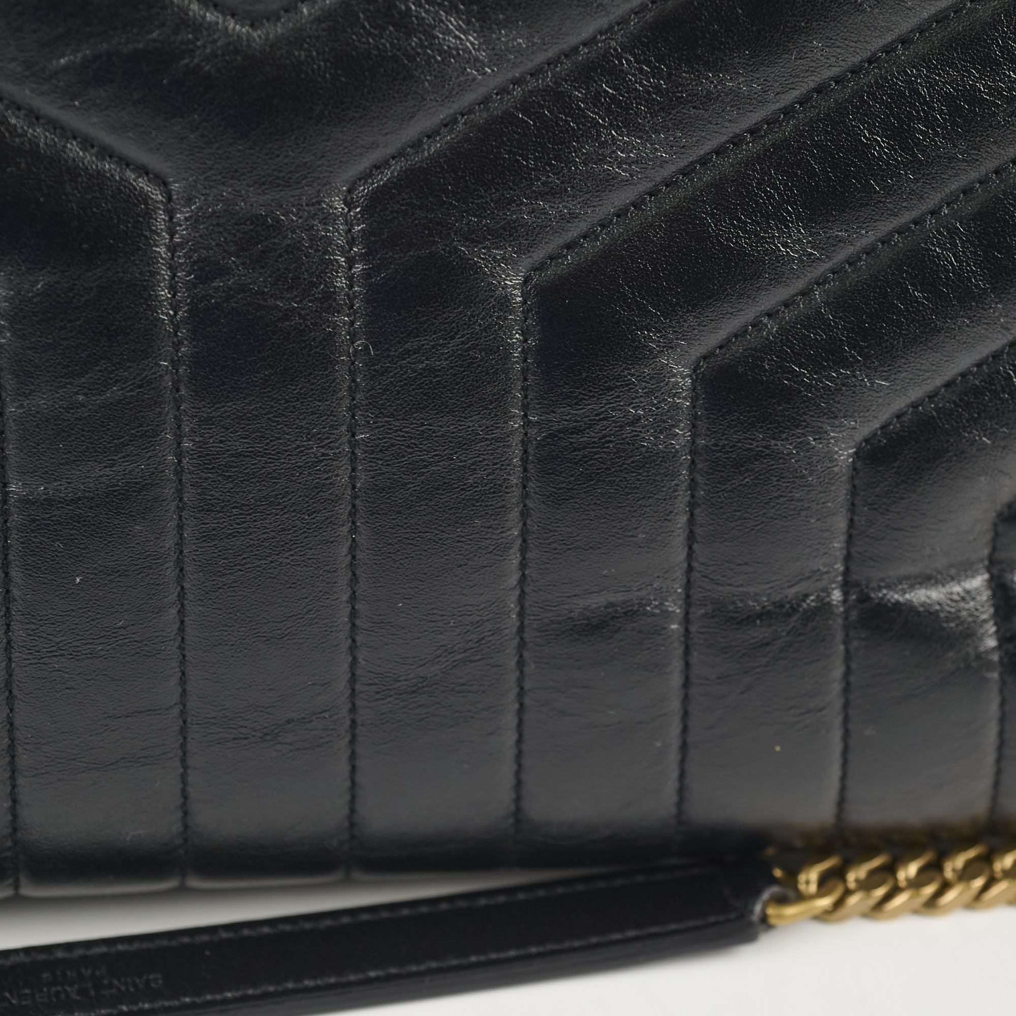 Close-up of a black quilted handbag with gold chain detail