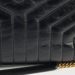 Close-up of a black quilted handbag with gold chain detail