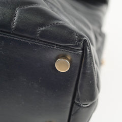 Close-up of a black leather bag with a gold metal button.