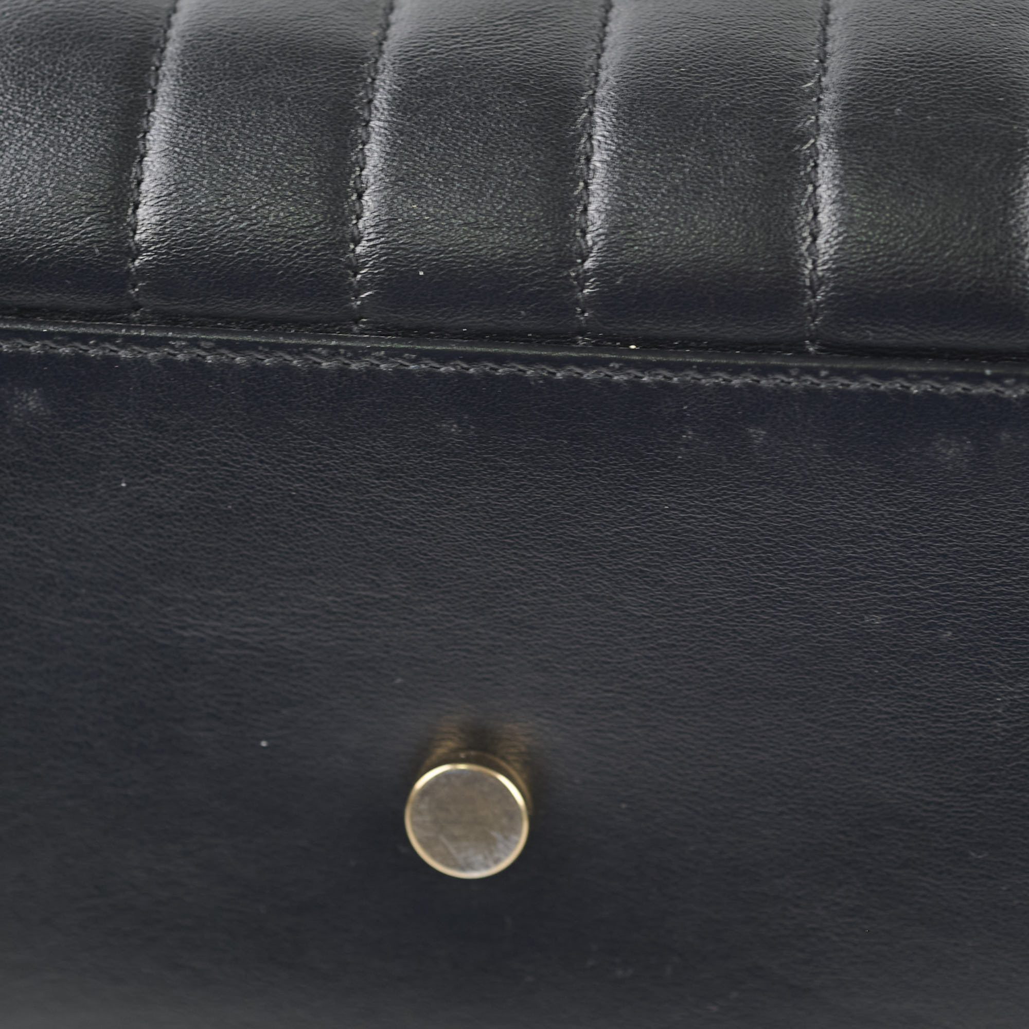 Close-up of a black leather bag with a gold clasp.