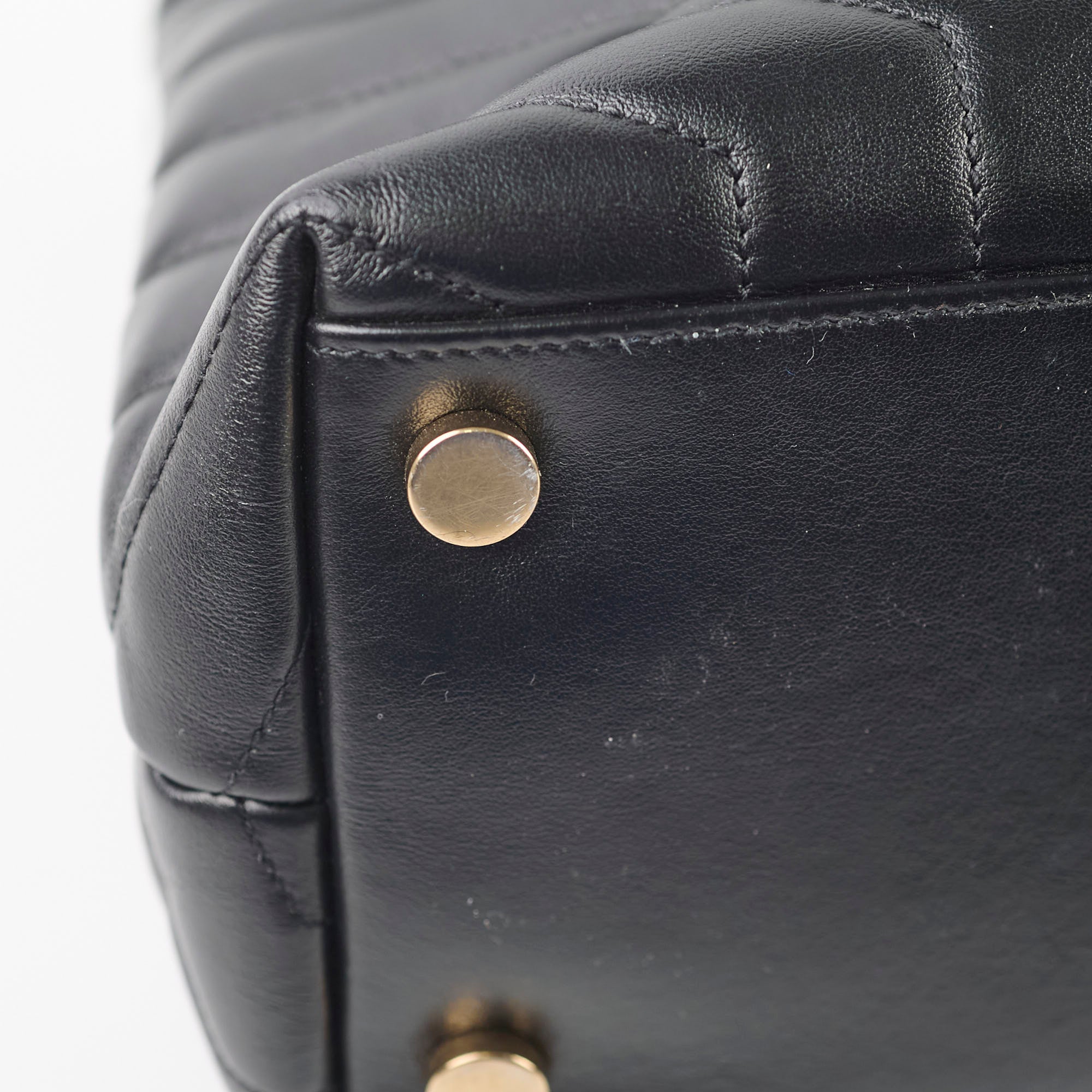 Close-up of a black leather handbag with gold hardware
