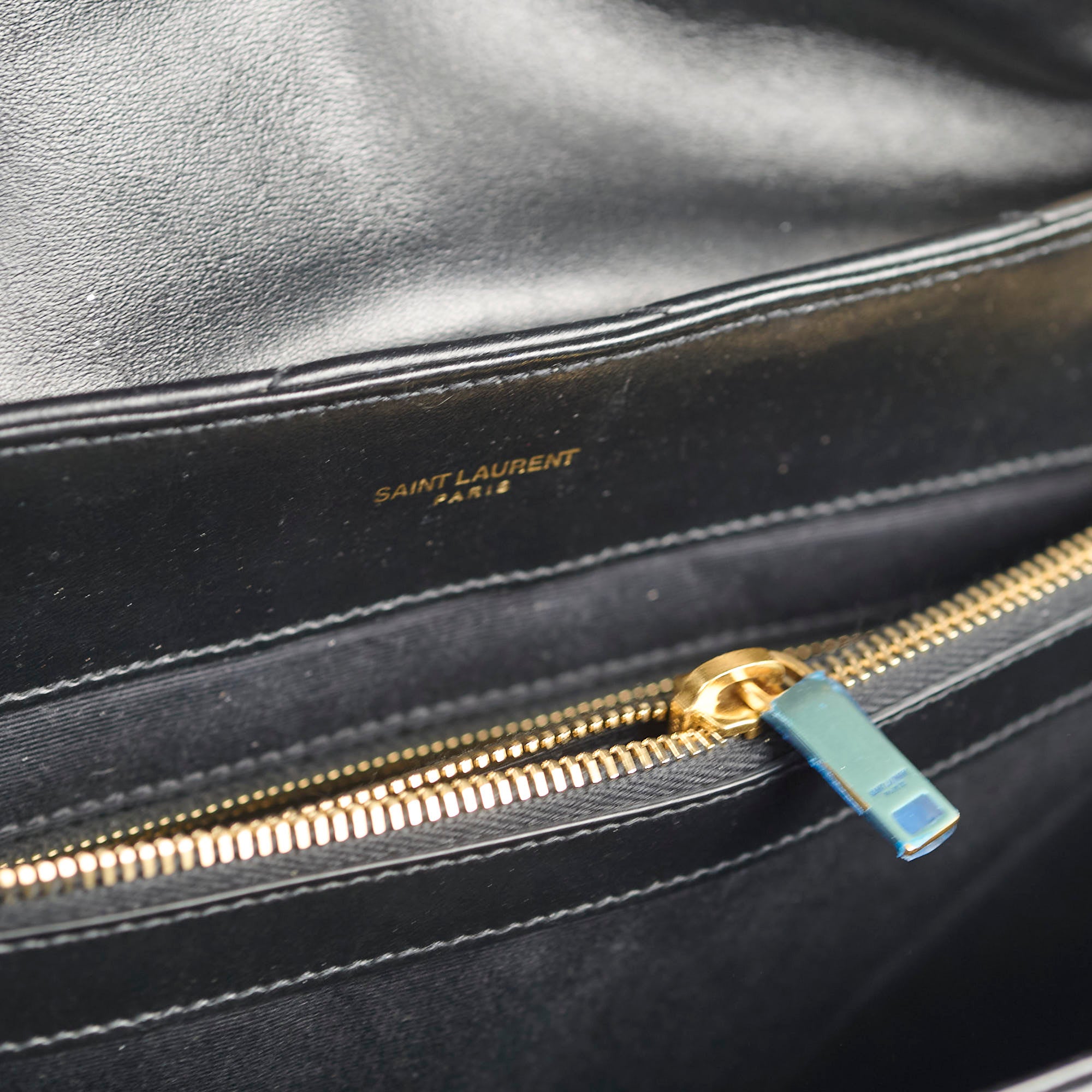 Black leather bag with gold zipper and 'Saint Laurent' branding.
