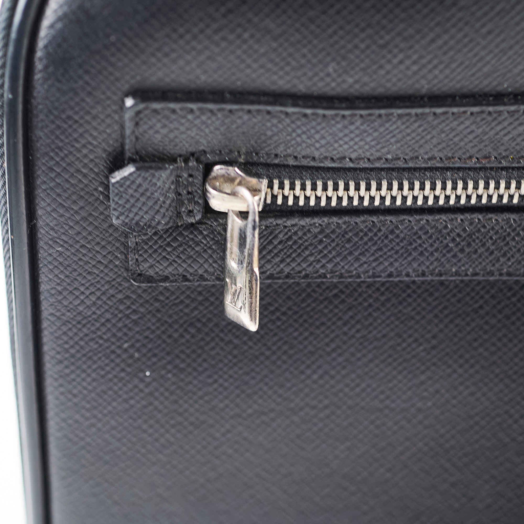 Close-up of a black textured suitcase with a silver zipper.