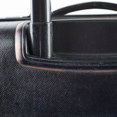Close-up of a black suitcase handle on a textured black surface