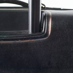 Close-up of a black suitcase handle on a textured black surface