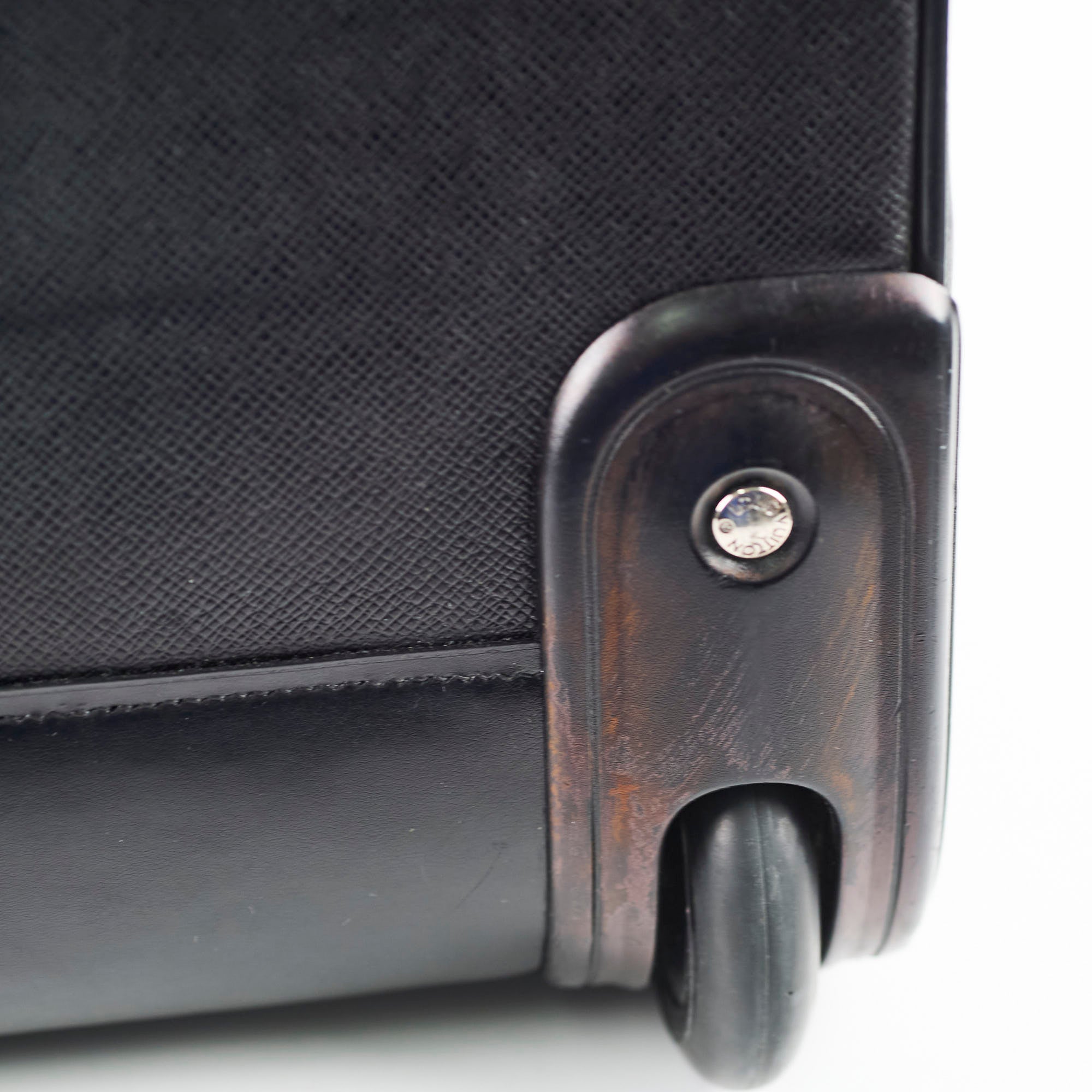 Close-up of a black suitcase wheel and handle 