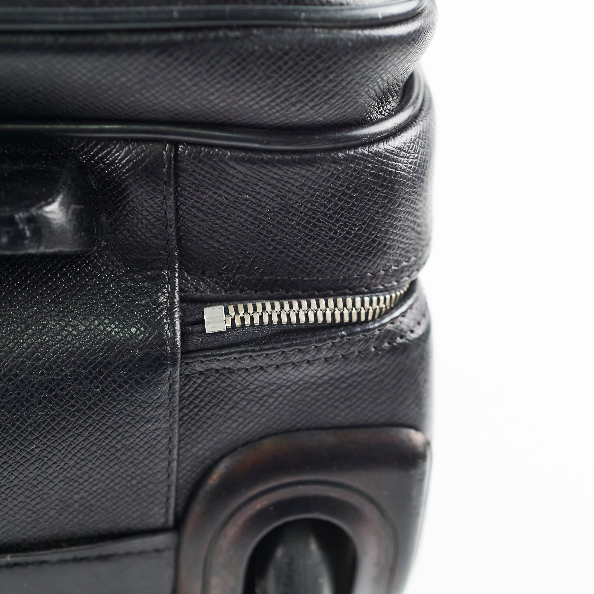 Close-up of a black textured suitcase with a zipper detail 