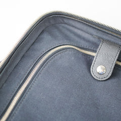 Close-up of a gray bag with a zipper and leather handle 
